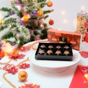 Gourmet Chocolate Gift Set in festive packaging under a Christmas tree, featuring ÉSOPHY Luxury Greek Pralines.