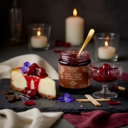 An elegant dessert serving of Navarino Icons Sour Cherry Spoon Sweet poured over cheesecake and presented in a crystal dessert glass.