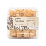 Close-up top view of Simantiraki Xerotigana box showing golden fried dough topped with crushed almonds.