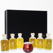 Six elenianna olive oil sample bottles and a red tasting glass displayed in front of the black presentation box