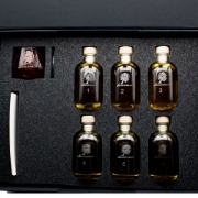 Foam insert inside the elenianna tasting kit with six numbered miniature olive oil bottles and a dedicated red tasting glass compartment